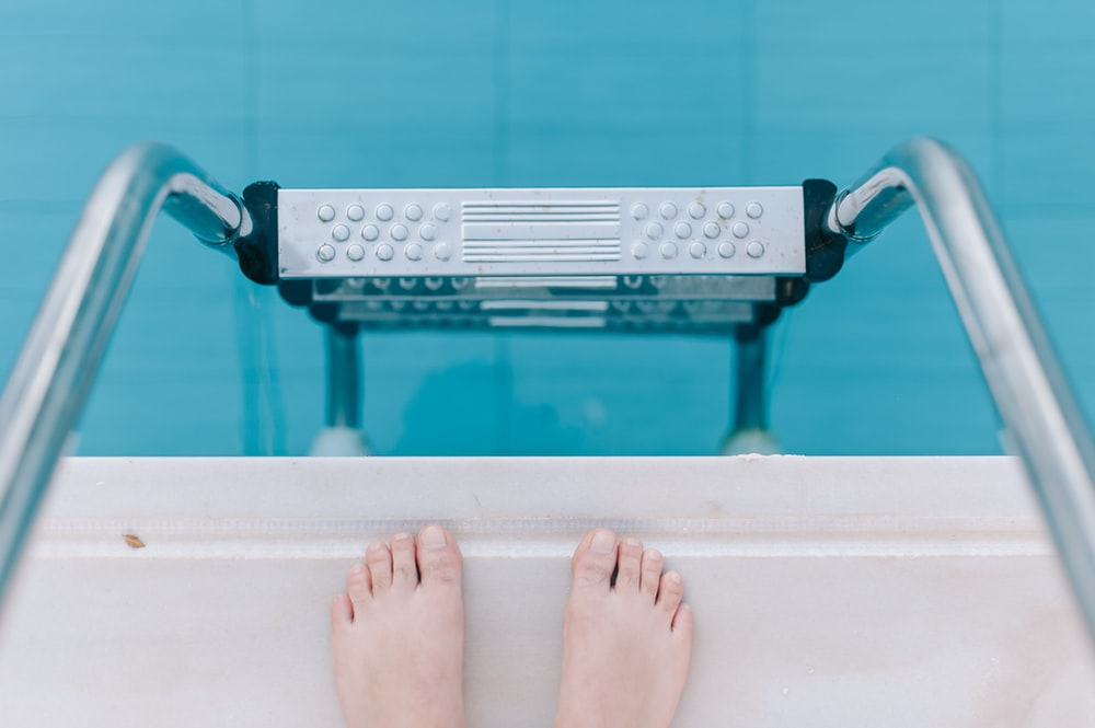 a person standing on the pools deck facing the pool’s steps