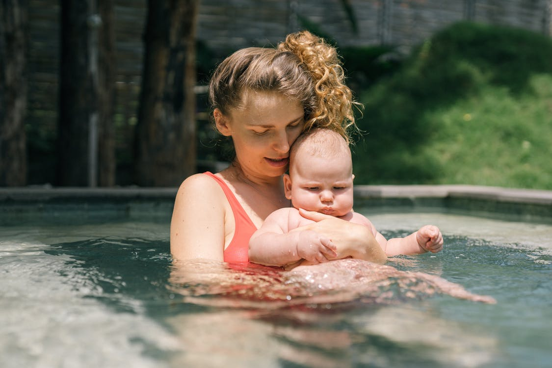 a mother helping her kid get in the pool