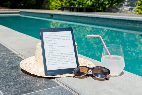 A tab and a drink placed at the side of the pool