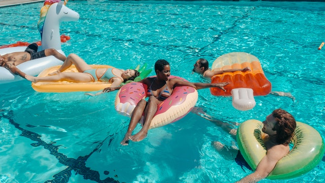 people swimming in the pool with tubes