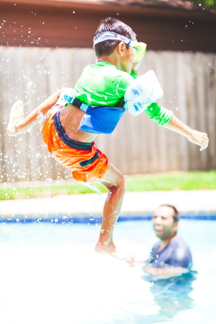 A boy cannonball diving into the swimming pool in Ashburn, VA