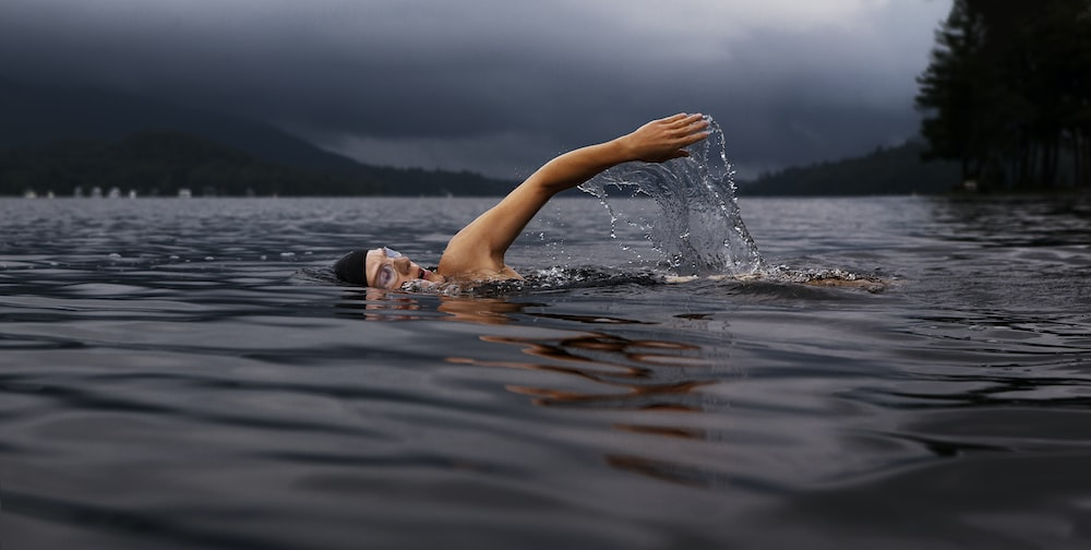 A man doing a full-body workout by swimming in a lake