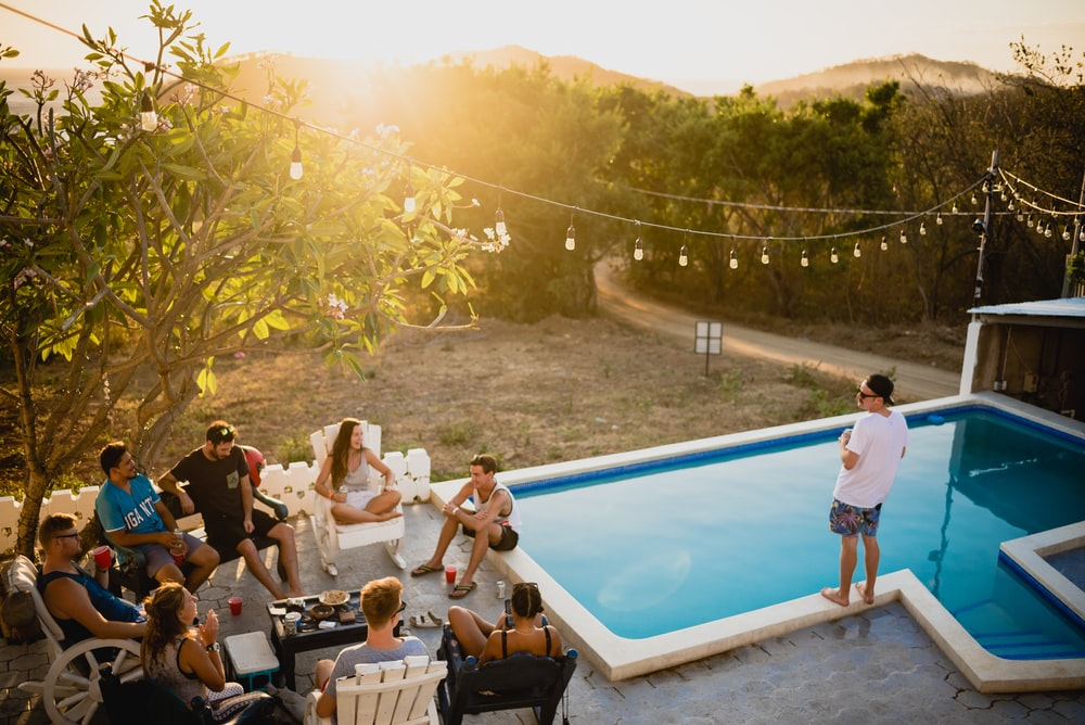 A group of friends gathered near a backyard swimming pool