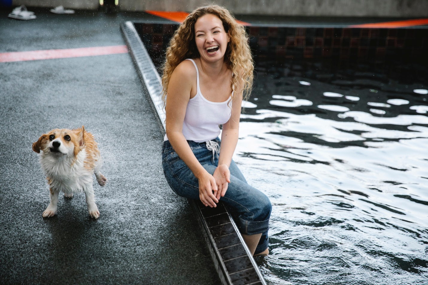 A woman smiling with her dog beside a pool