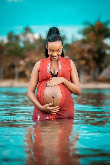 A pregnant woman standing on the beach.