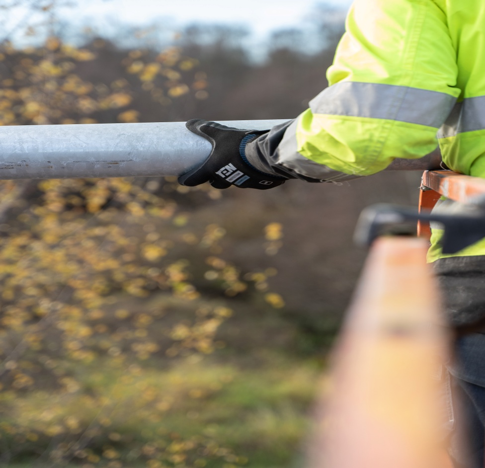 A man holdings a pipe with gloves on